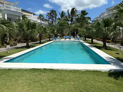 a large swimming pool in a yard with palm trees at Apartment en residence face à la Mer in Las Terrenas