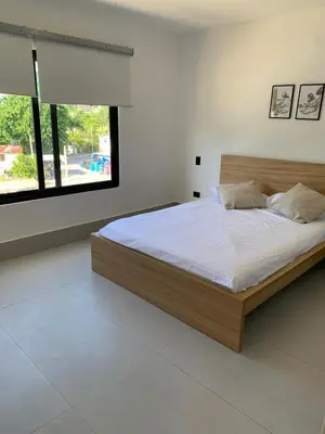 a bedroom with a large bed with white sheets and a window at Prado Suites Luxurious Apartment for Long Term Stay in Las Terrenas