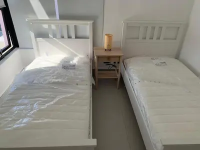 two white beds in a small room with a night stand at Prado Suites Luxurious Apartment for Long Term Stay in Las Terrenas