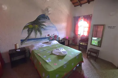a bedroom with a green bed with a painting on the wall at Hotel El Rancho Sosua in Sosúa