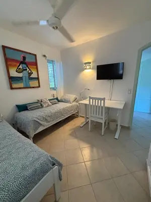 a room with two beds and a desk and a tv at Waterfront apartment in Las Terrenas