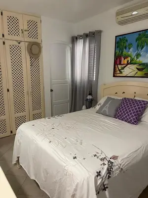 a bedroom with a white bed and a painting on the wall at Waterfront apartment in Las Terrenas
