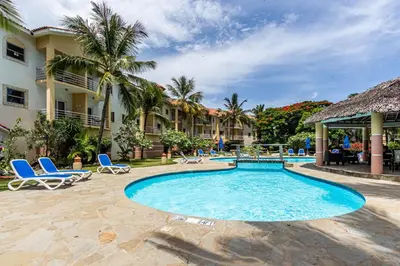 a pool at a resort with blue chairs and palm trees at Garden Studio, Ocean Dream in Cabarete
