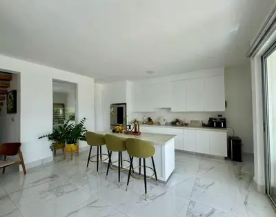 a kitchen with white cabinets and bar stools at Villa Noah in Bayahibe