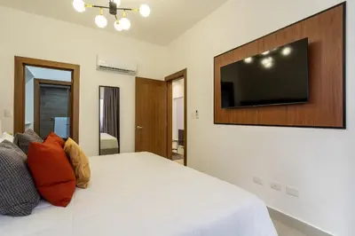 a bedroom with a large bed with a flat screen tv on the wall at Splendid-KingBed-3BR-Pool-AC-Modern-WiFi-Yellowkey in Santo Domingo
