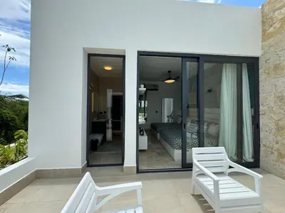 two white chairs on a balcony with a bedroom at Golf 218 Playa Nueva Romana in San Pedro de Macorís