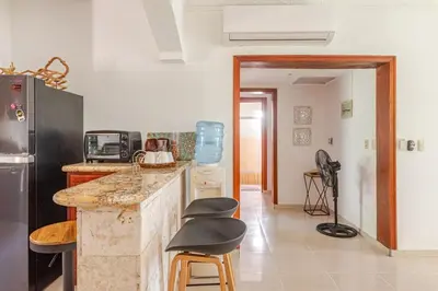 a kitchen with a counter and stools and a refrigerator at Spacious 2 Bedroom Condo with Pool close to Beach in Punta Cana
