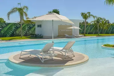 two chairs and an umbrella next to a swimming pool at Cana Rock Star in Punta Cana
