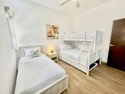 a white bedroom with a bunk bed and a ladder at Peaceful 2BR 2BA in Bonita with Pool and Palm Tree Views in Las Terrenas