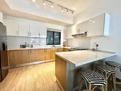 a kitchen with white cabinets and a counter with stools at Peaceful 2BR 2BA in Bonita with Pool and Palm Tree Views in Las Terrenas