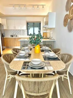 a dining room table with chairs and a yellow vase at Peaceful 2BR 2BA in Bonita with Pool and Palm Tree Views in Las Terrenas