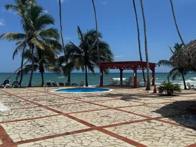 a resort with a pavilion and palm trees on the beach at Sea front apartment, Juan Dolio, San Pedro in San Pedro de Macorís