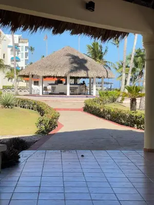 a pavilion with a straw umbrella and the ocean at Sea front apartment, Juan Dolio, San Pedro in San Pedro de Macorís