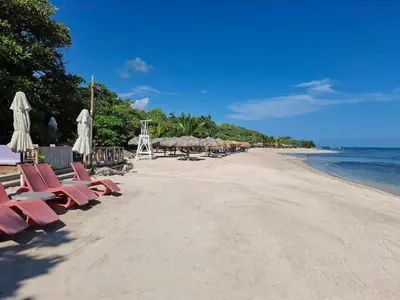 a beach with chairs and umbrellas and the ocean at Beach Apartment with Pool - Costambar in Las Flores