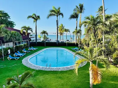 an empty swimming pool with palm trees and the ocean at Romantic Beachfront Retreat In Las Terrenas - Everything You Could Want - 2 Rooms in Las Terrenas
