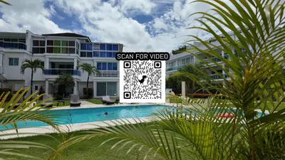 a sign in front of a pool in a building at La Fenice Beachfront Apartment in Las Terrenas