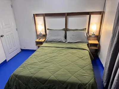 a bedroom with a green bed with two night stands at enjoy the nature of the countryside in Bonao