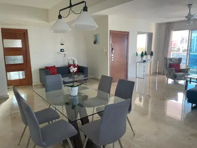 a dining room and living room with a glass table and chairs at Amplio y acogedor apto céntrico de 3 habitaciones in Santo Domingo