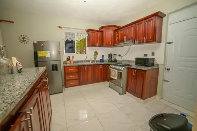 a kitchen with wooden cabinets and a stainless steel refrigerator at JARABACOA villa Almonte in Jarabacoa