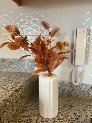 a white vase with a plant in it on a counter at Apartamento acogedor con estilo y piscina in La Romana
