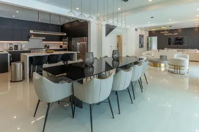 a large kitchen with a bar with white chairs at Casa Deco in La Romana