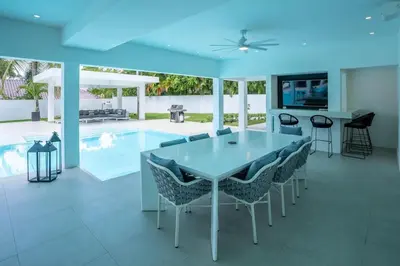 a dining room with a table and chairs and a swimming pool at Casa Deco in La Romana