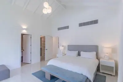 a white bedroom with a large bed and two tables at Casa Deco in La Romana
