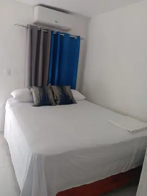 a bed in a room with a blue curtain at Hospedaje Las Flores Pedernales in Pedernales