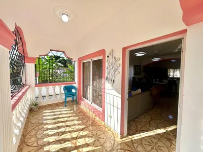 a house with a balcony with a blue chair at Villa Rosa 3 Habitaciones Balcones Aire Acondicionado Espacio Ideal Para Tu Familia O Grupo in Río San Juan