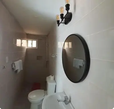 a bathroom with a white toilet and a mirror at Hospedaje Las Flores in Pedernales
