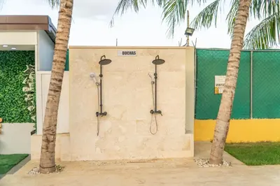 a wall with three shower stalls next to two palm trees at Terrenal Paradise in Esperanza