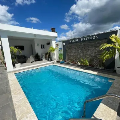 a large blue swimming pool in front of a house at Vintage Villa confortable apartments Wifi private pool free parking in Boca Chica