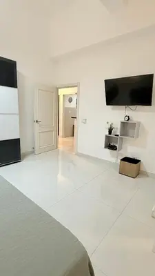 a white room with a bed and a flat screen tv at Soho loft residence in Santo Domingo