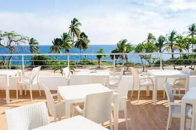 a restaurant with white tables and chairs and the ocean at Confortable apartamento a 10 min del aeropuerto in La Viva