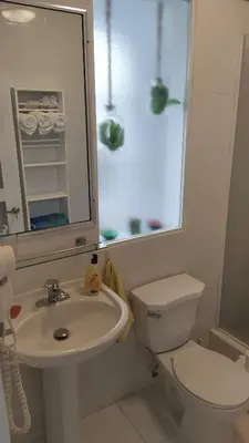 a white bathroom with a toilet and a sink at Cabarete Heartbeat Suite, 1 BR in Cabarete