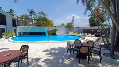 a pool with tables and chairs in front of a building at Cabarete Heartbeat Suite, 1 BR in Cabarete