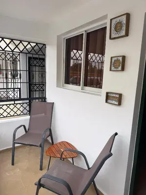 two chairs and a clock on a balcony at Acogedor y céntrico apartamento en Palmas de Gurabo in Santiago de los Caballeros