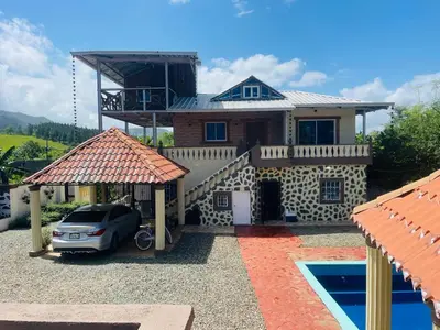 a house with a car parked in front of it at Villa de Grupo 16, Piscina Natural, Jacuzzi, Granja y Mascotas, Rosa & Deivi te esperan in Villa Altagracia