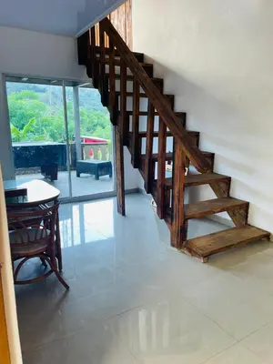 a wooden staircase in a room with a table and chairs at Villa de Grupo 16, Piscina Natural, Jacuzzi, Granja y Mascotas, Rosa & Deivi te esperan in Villa Altagracia