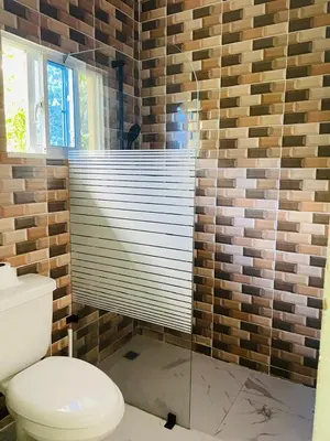 a bathroom with a toilet and a glass shower at Villa de Grupo 16, Piscina Natural, Jacuzzi, Granja y Mascotas, Rosa & Deivi te esperan in Villa Altagracia