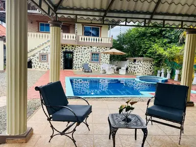 two chairs and a table next to a swimming pool at Villa de Grupo 16, Piscina Natural, Jacuzzi, Granja y Mascotas, Rosa & Deivi te esperan in Villa Altagracia