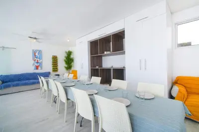 a dining room with a long table and white chairs at La casa del Maestro apartment in Bayahibe