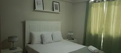 a bedroom with a white bed with a green curtain at Apartamento en Boca Chica T3 602 in Boca Chica