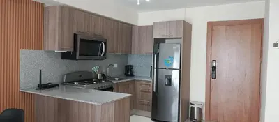 a kitchen with wooden cabinets and a stainless steel refrigerator at Apartamento en Boca Chica T3 602 in Boca Chica