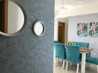 a dining room with blue chairs and a mirror at Apartamento en Boca Chica T2 501 in Boca Chica