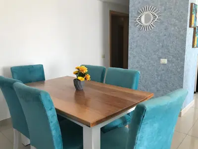 a dining room table with blue chairs and a vase with flowers at Apartamento en Boca Chica T2 501 in Boca Chica