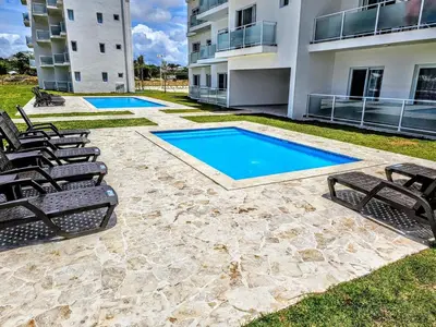 a patio with chairs and a swimming pool in front of a building at NEW Luxury at Sosua Ocean Village Laguna City in Sosúa