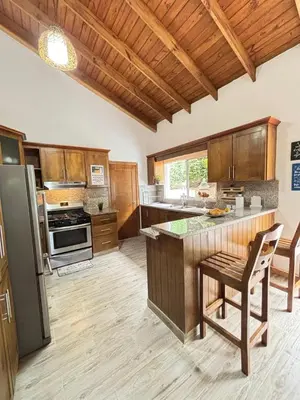 a large kitchen with wooden cabinets and a refrigerator at Villa escondida in San Cristóbal