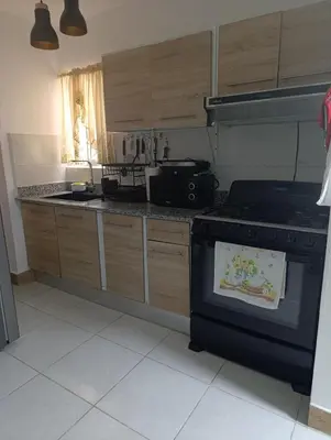 a kitchen with a stove and wooden cabinets at Comfort, safety and close to everything in Los Paredones