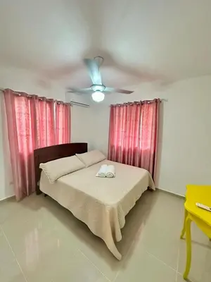 a bedroom with a bed with red curtains and a ceiling fan at Modern, Elegant & Comfortable Apartment in El Seis